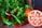 Photo of a smiling restaurant owner holding fresh vegetables in a kitchen.