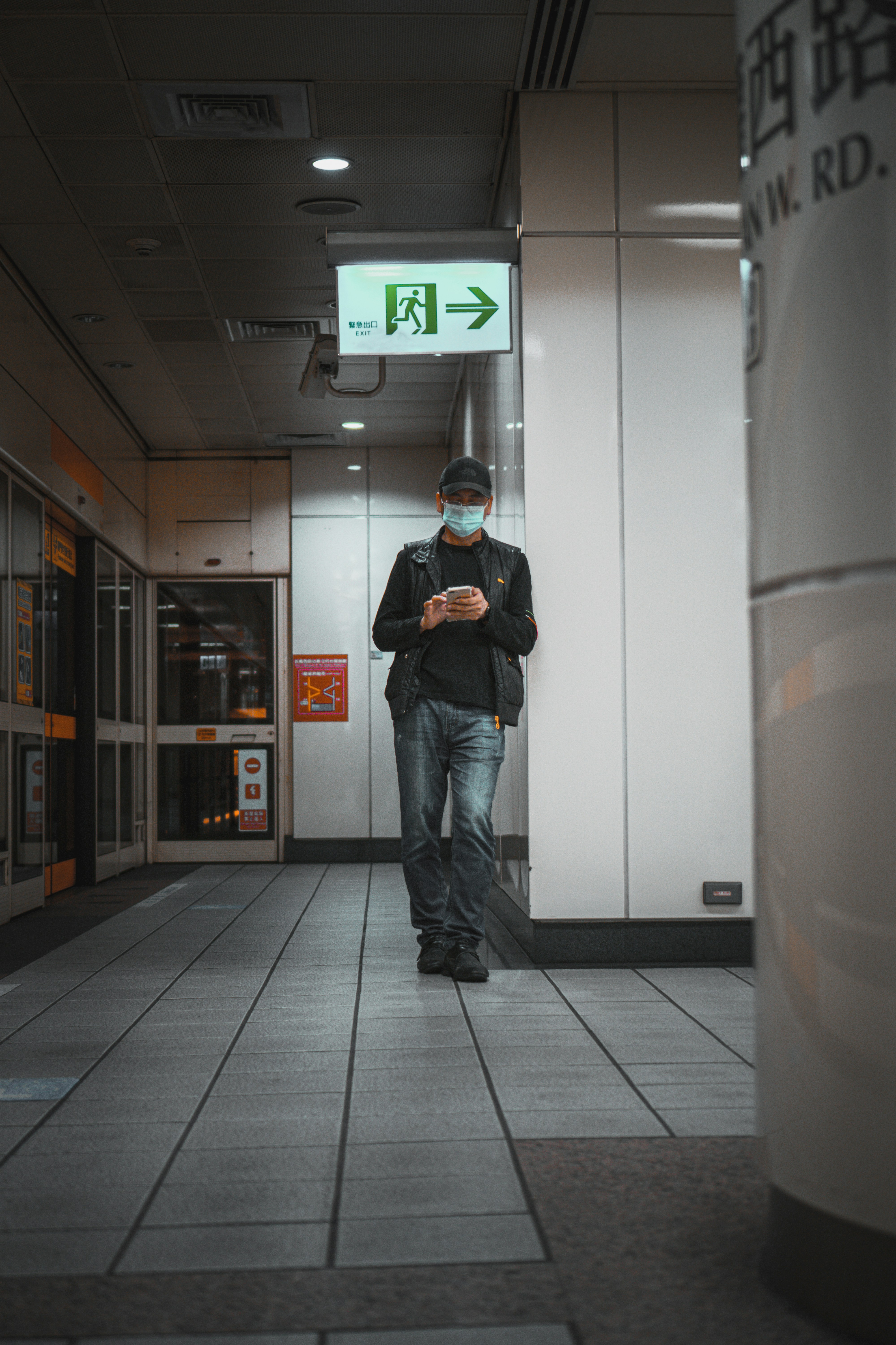 man in black jacket and blue denim jeans wearing black and white headphones
