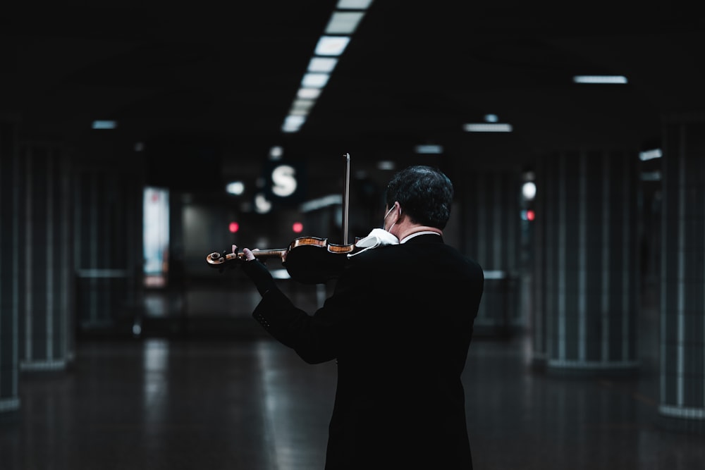 Mann im schwarzen Anzug spielt Geige