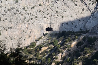 A detailed shot of a tunnel entrance carved into rugged mountain terrain, highlighting structural design.