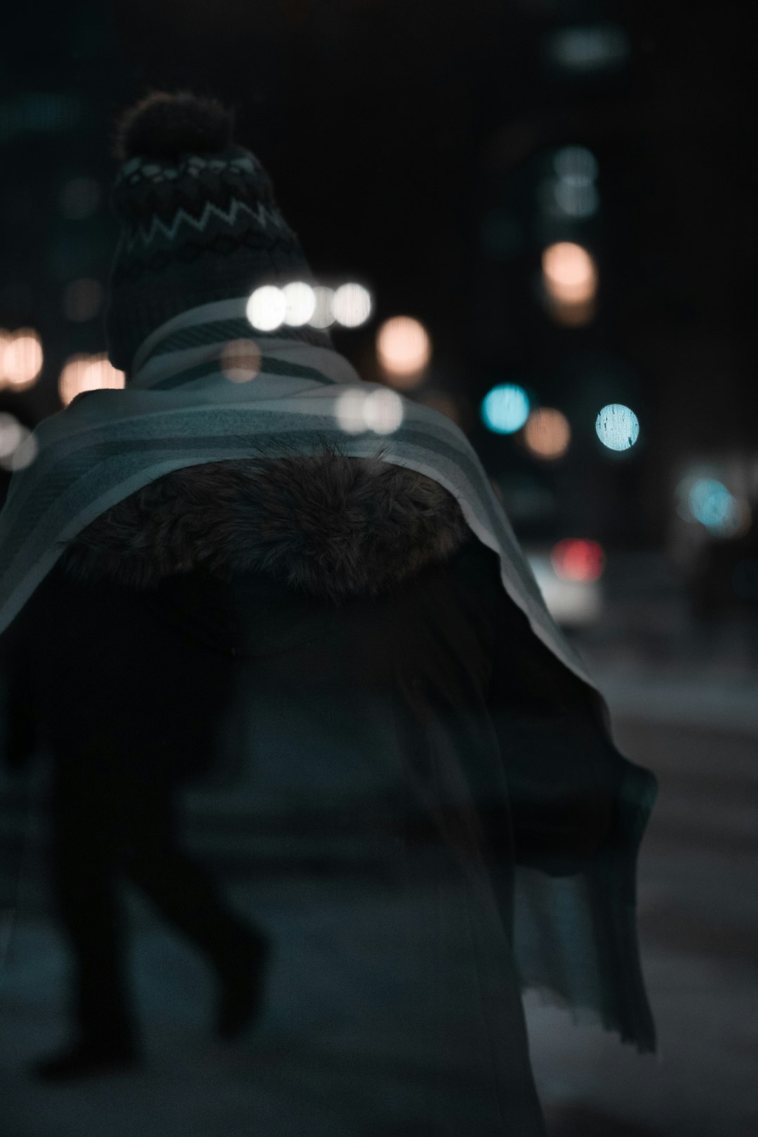 person in black fur coat standing on street during night time