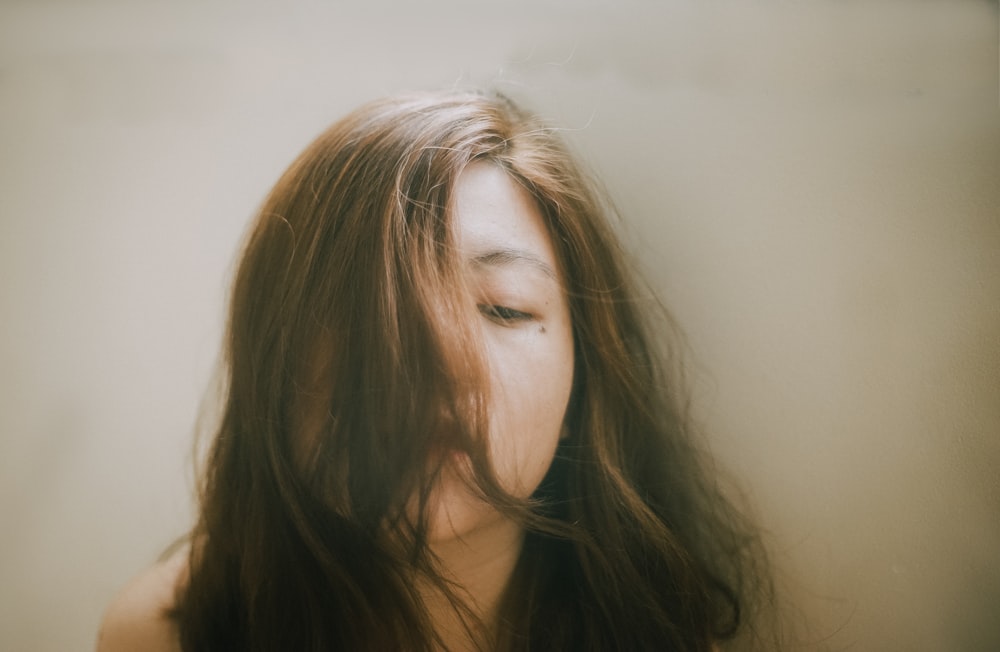 mujer con cabello rubio frente a la pared blanca