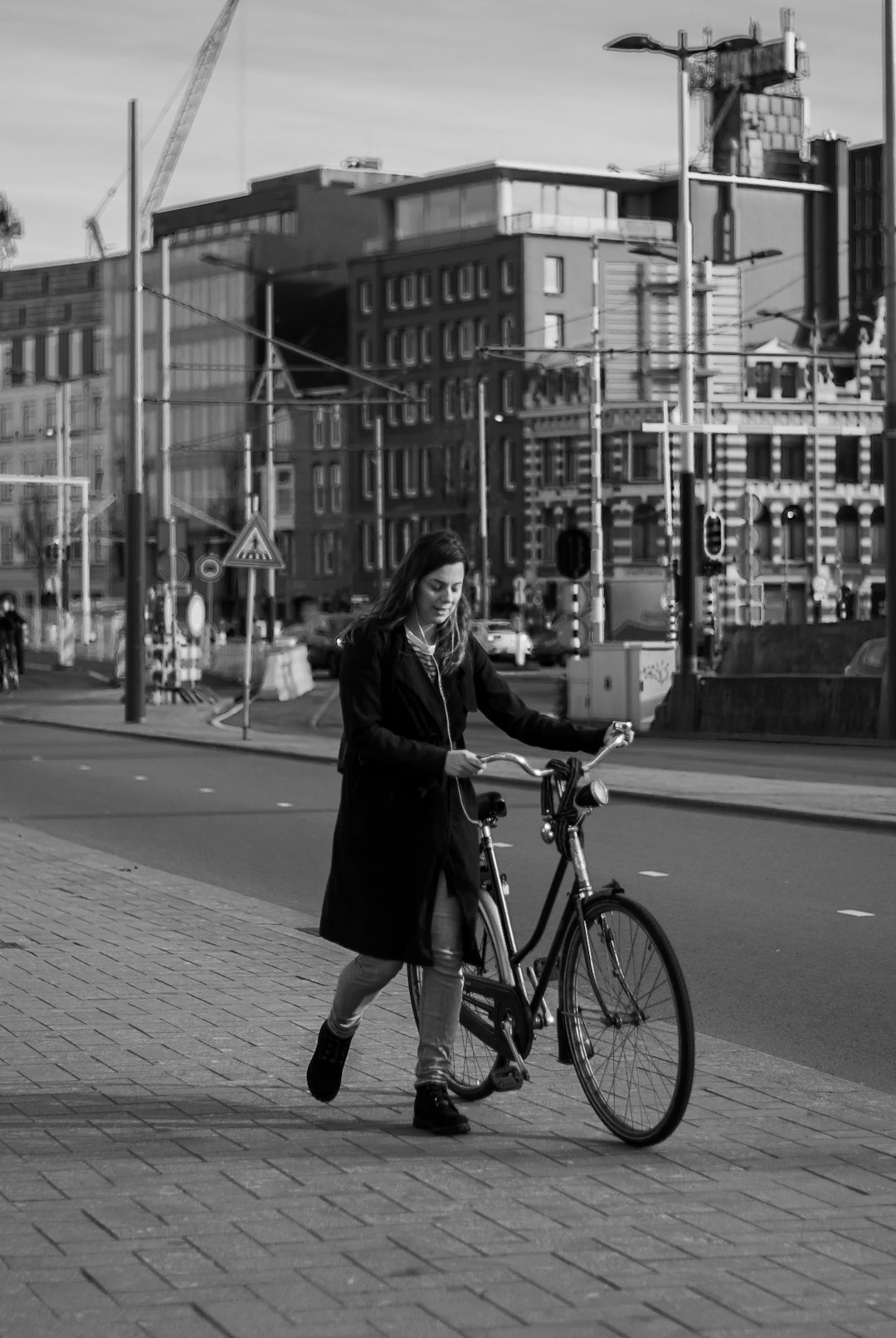 woman in black coat and black pants riding on bicycle on road during daytime
