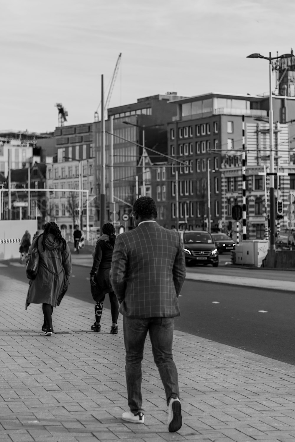 man and woman walking on sidewalk in grayscale photography