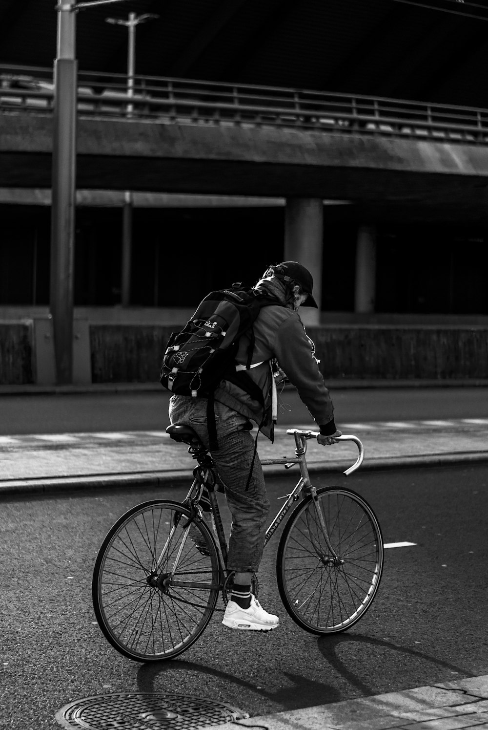 검은 재킷과 바지를 입은 남자가 낮 동안 도로에서 자전거를 타고 있다