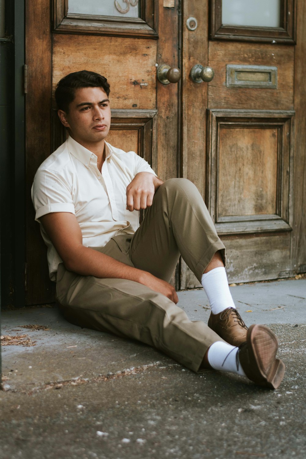 man in white button up shirt and brown pants sitting on concrete floor