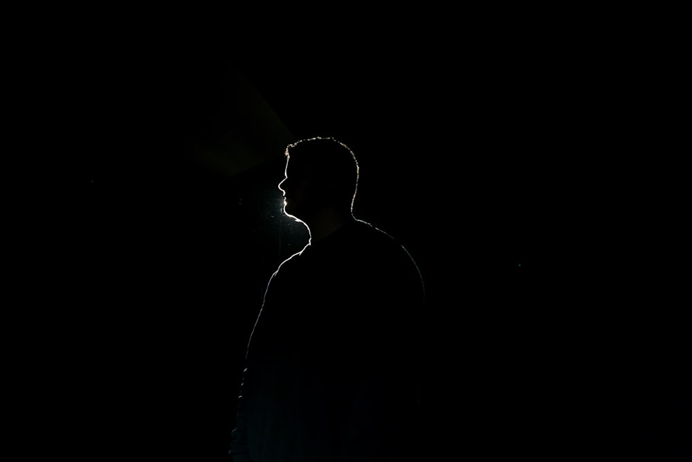 silhouette of man standing in dark room