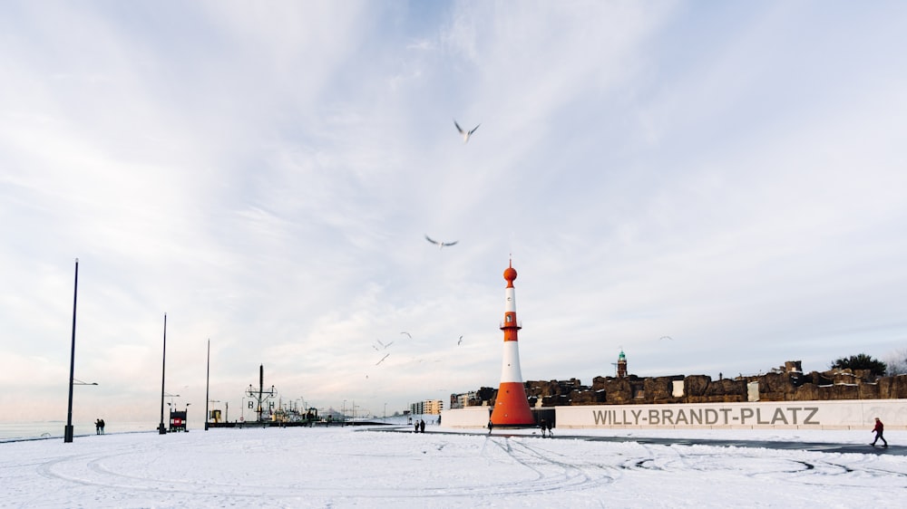 brown and white lighthouse on snow covered ground under cloudy sky during daytime