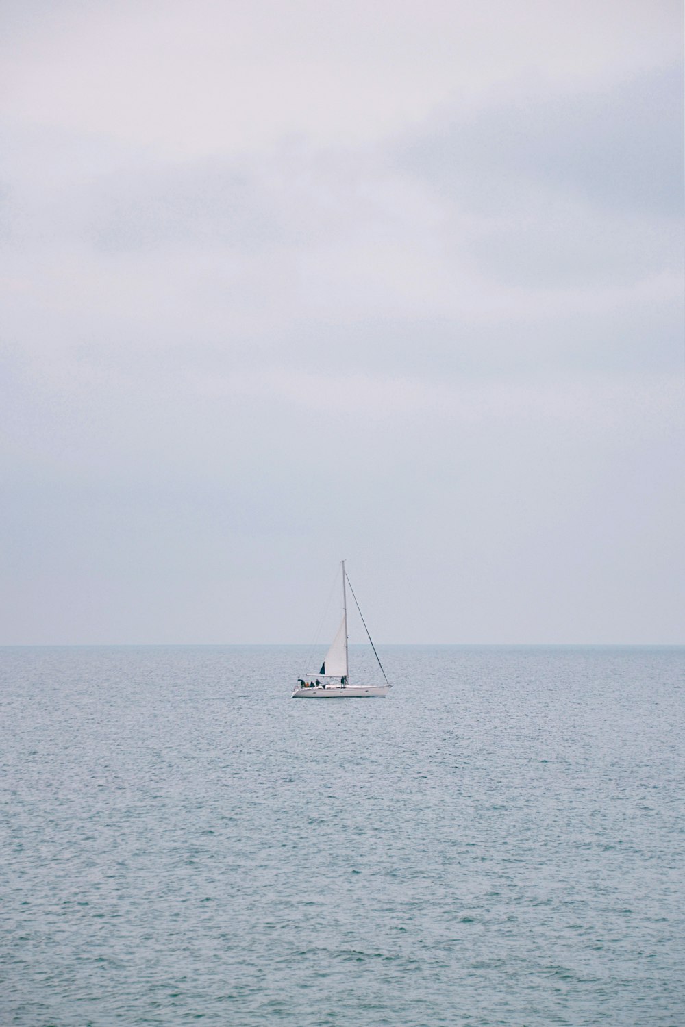 white sailboat on sea under white sky during daytime