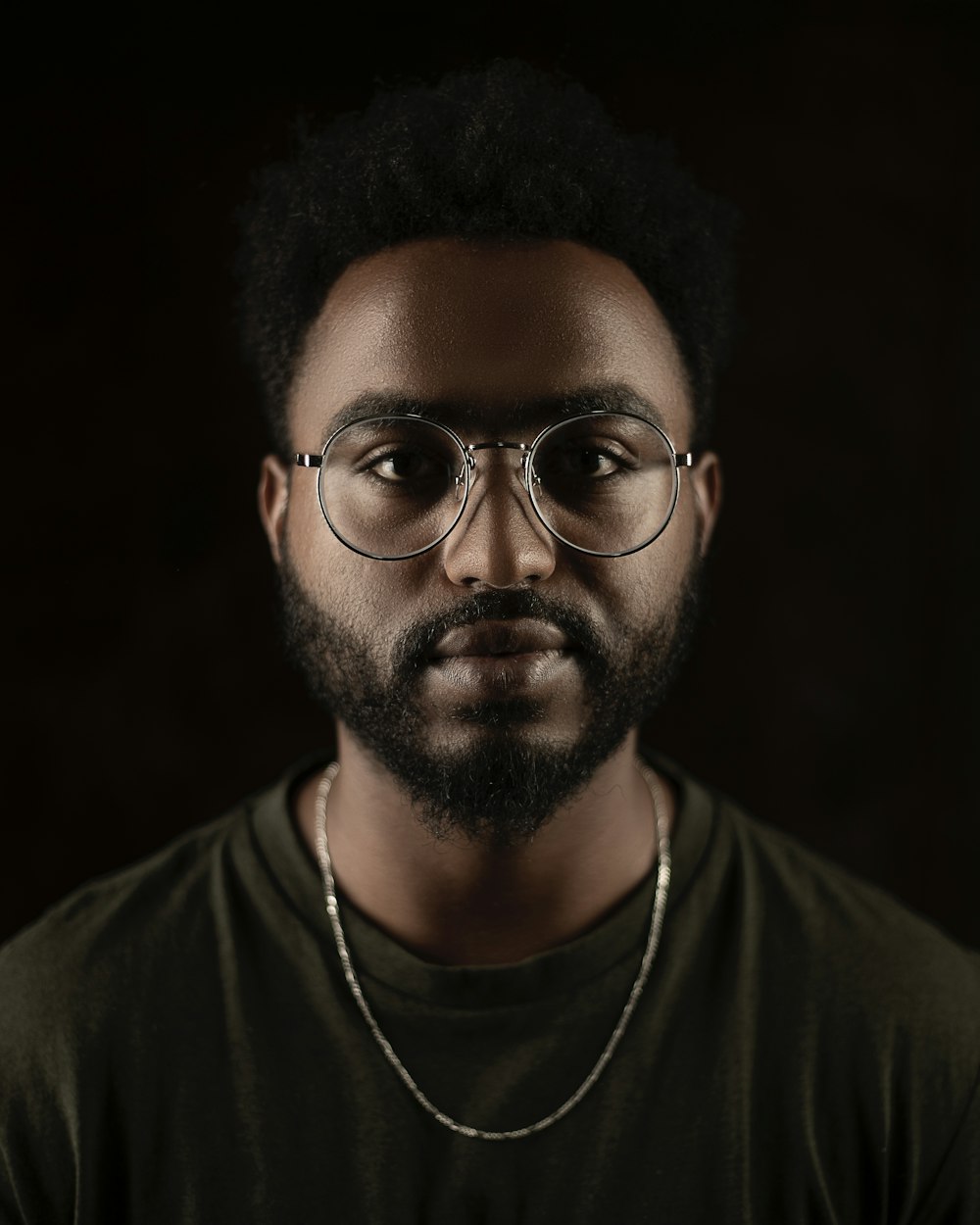 a man with a beard and glasses in a dark room