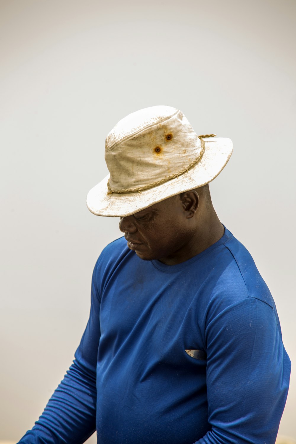 man in blue crew neck shirt wearing white fedora hat