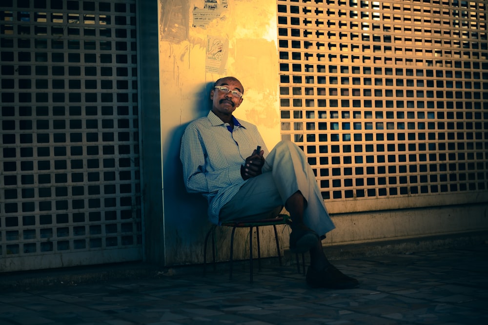 man in blue dress shirt and black pants sitting on brown wooden bench