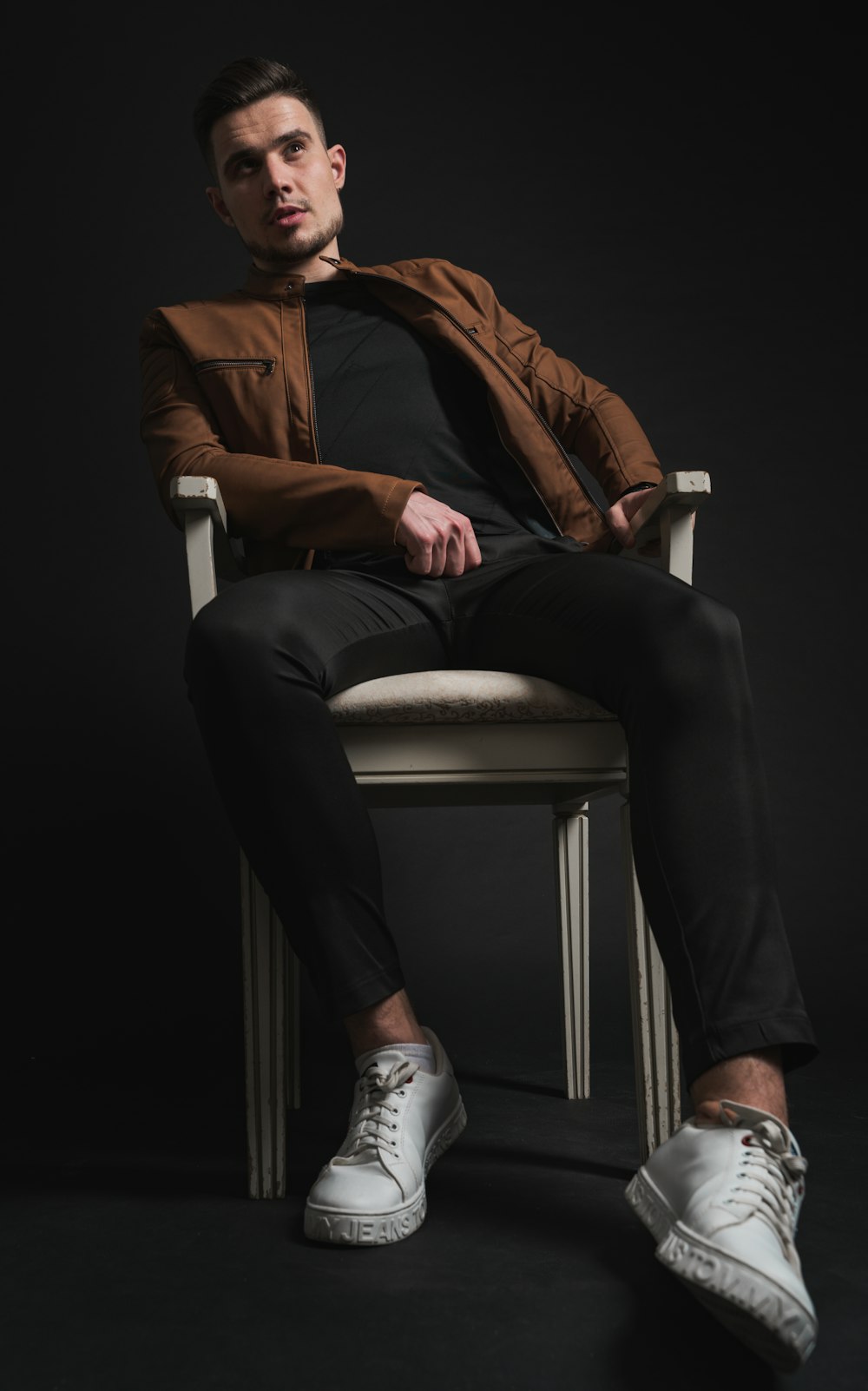 man in brown suit jacket and black dress pants sitting on white chair