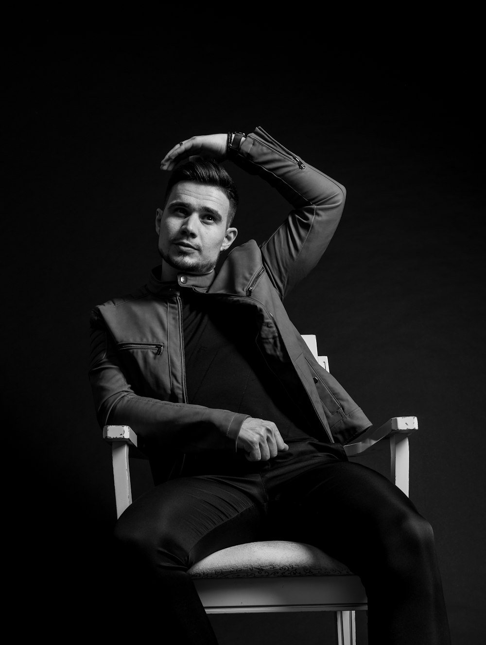 grayscale photo of woman in black blazer sitting on white plastic chair