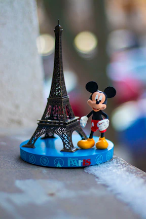 mickey mouse figurine beside eiffel tower miniature