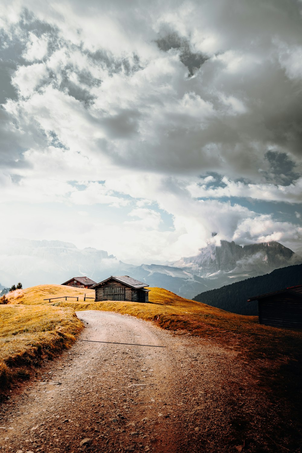 brown wooden house on brown field under white clouds during daytime