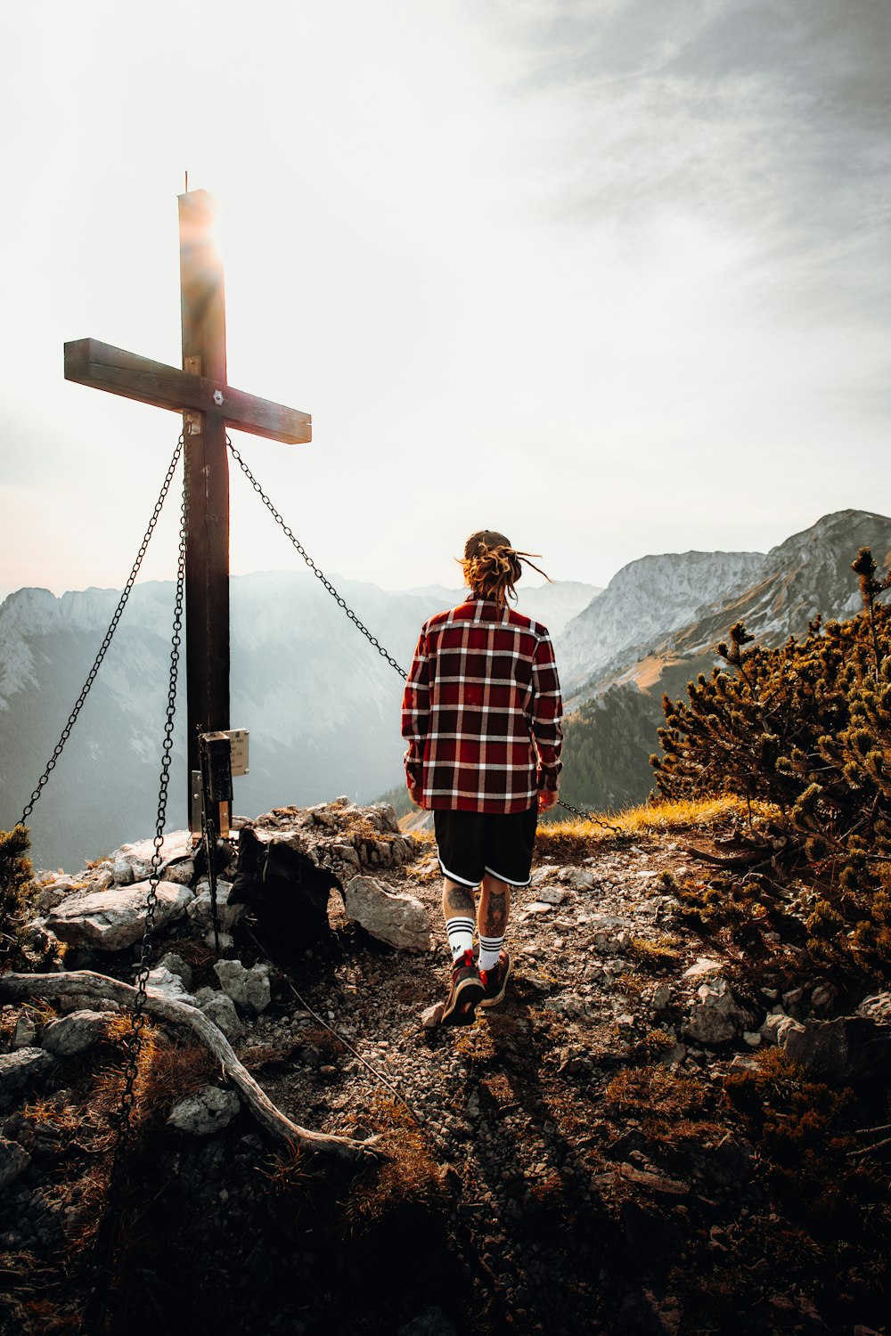 woman in red and black plaid dress shirt standing on brown wooden cross during daytime