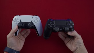 Two hands hold video game controllers against a red background. One controller is a white PlayStation 5 DualSense, and the other is a black PlayStation 4 DualShock.