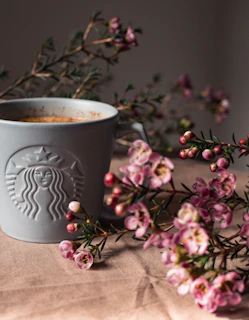 A cozy scene featuring a personalized mug with a soft pastel floral design on a wooden table next to a small daisy accent.