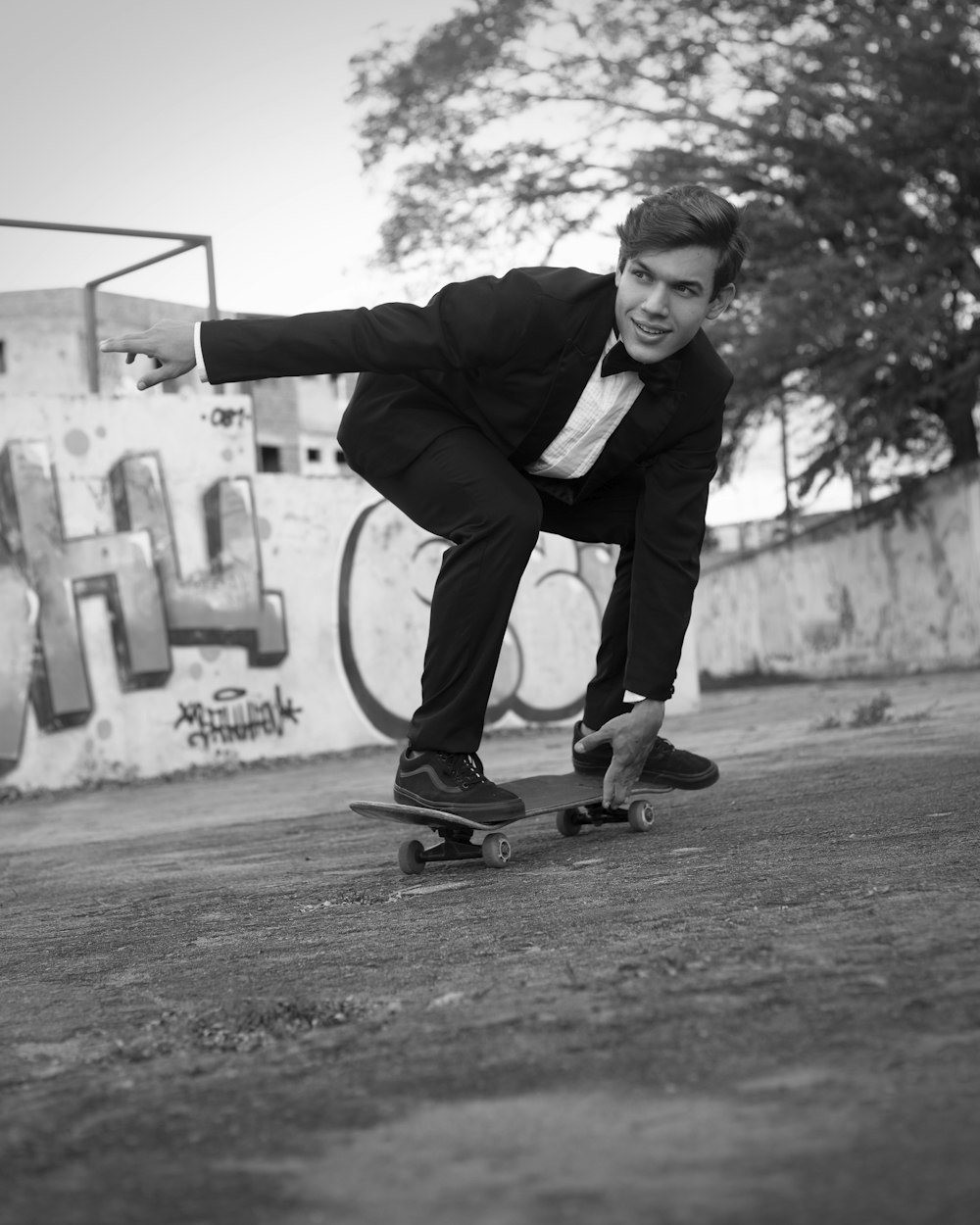 man in black suit jacket and pants standing beside white wall