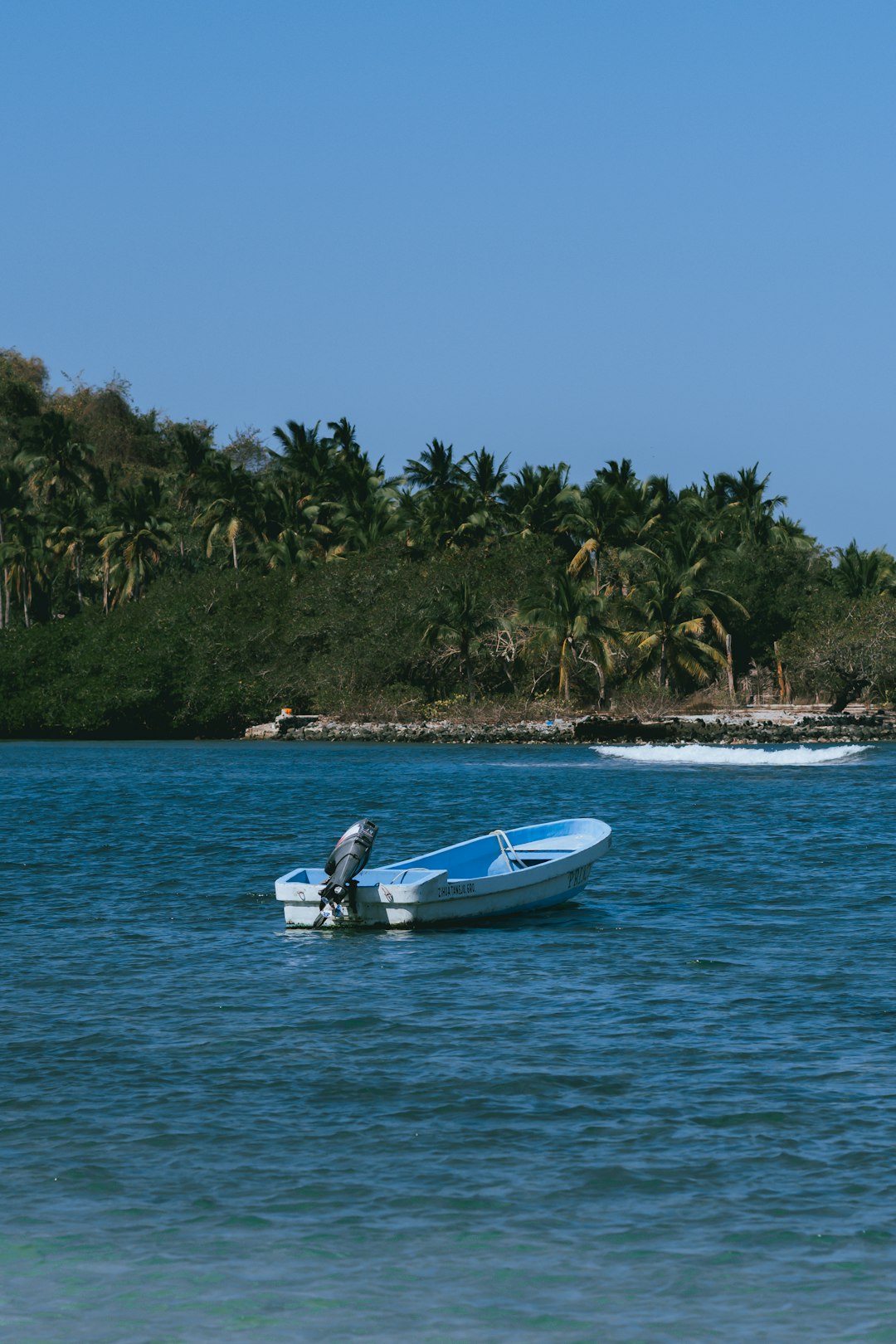 man in white shirt riding white and blue boat on blue sea during daytime