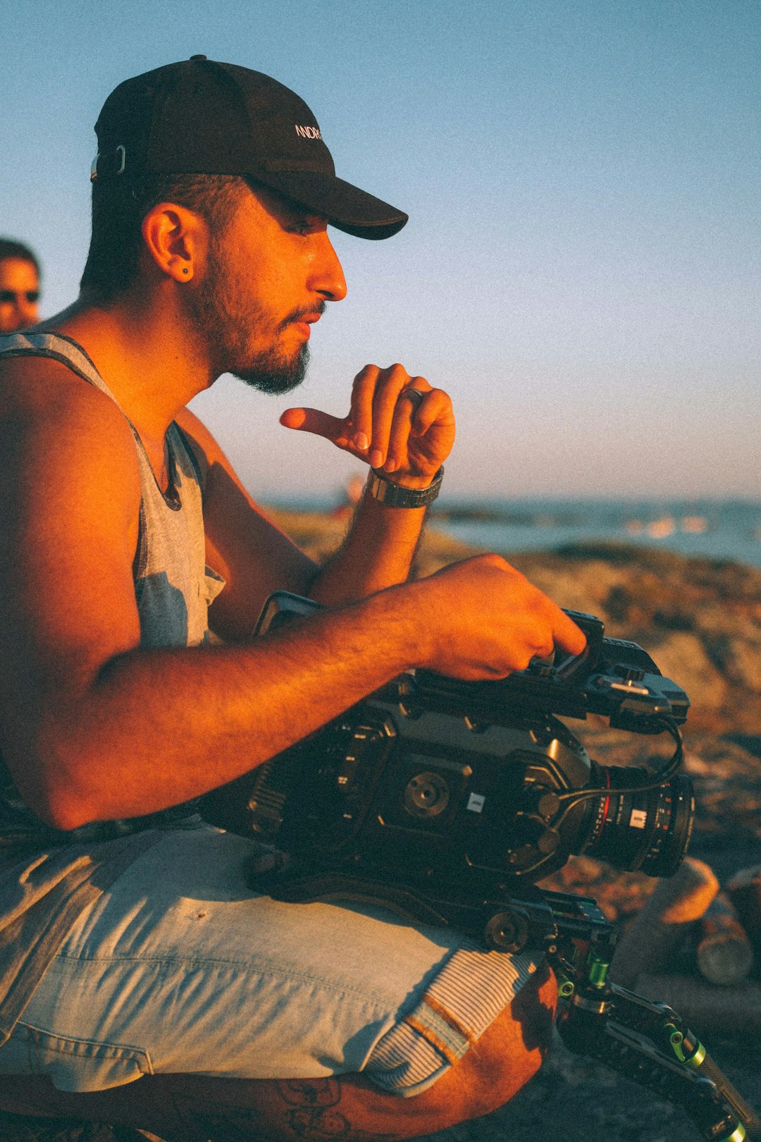 man in white tank top holding black dslr camera