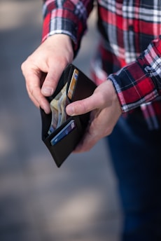 person holding a wallet searching for money