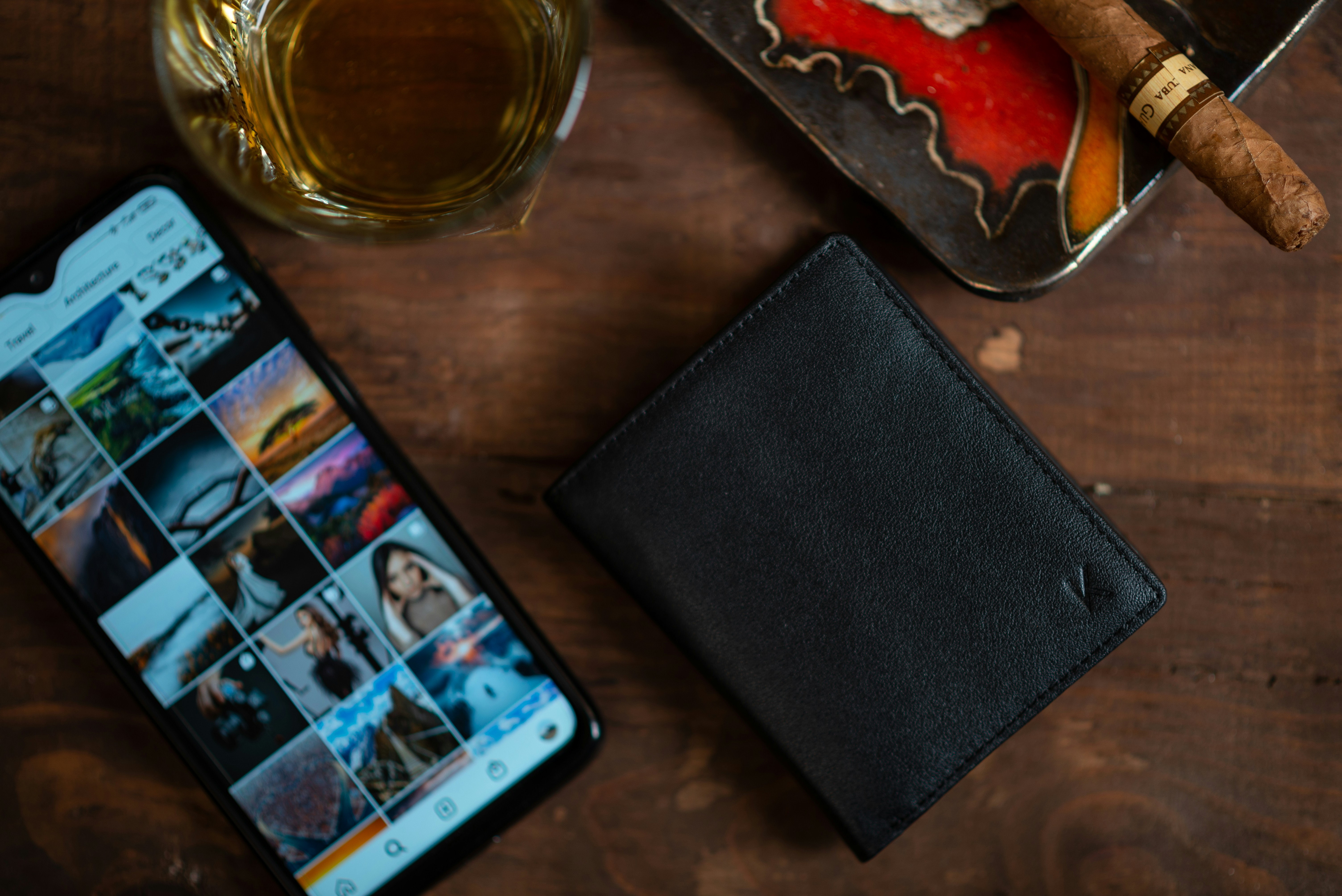 black leather bifold wallet beside clear glass mug