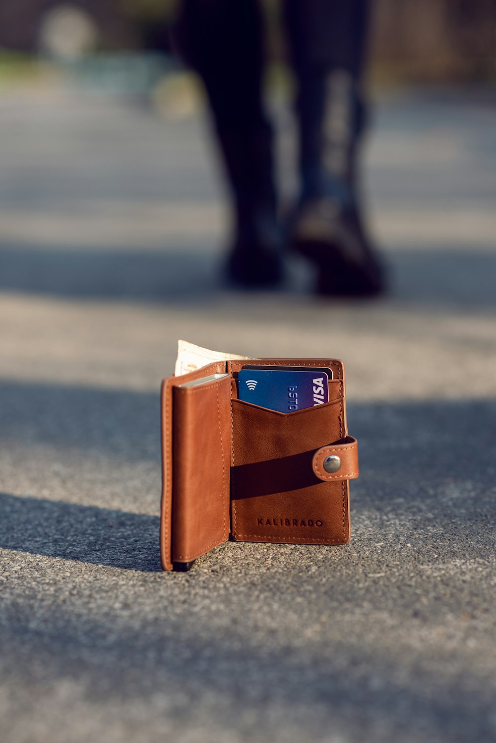 brown leather bifold wallet on gray concrete floor