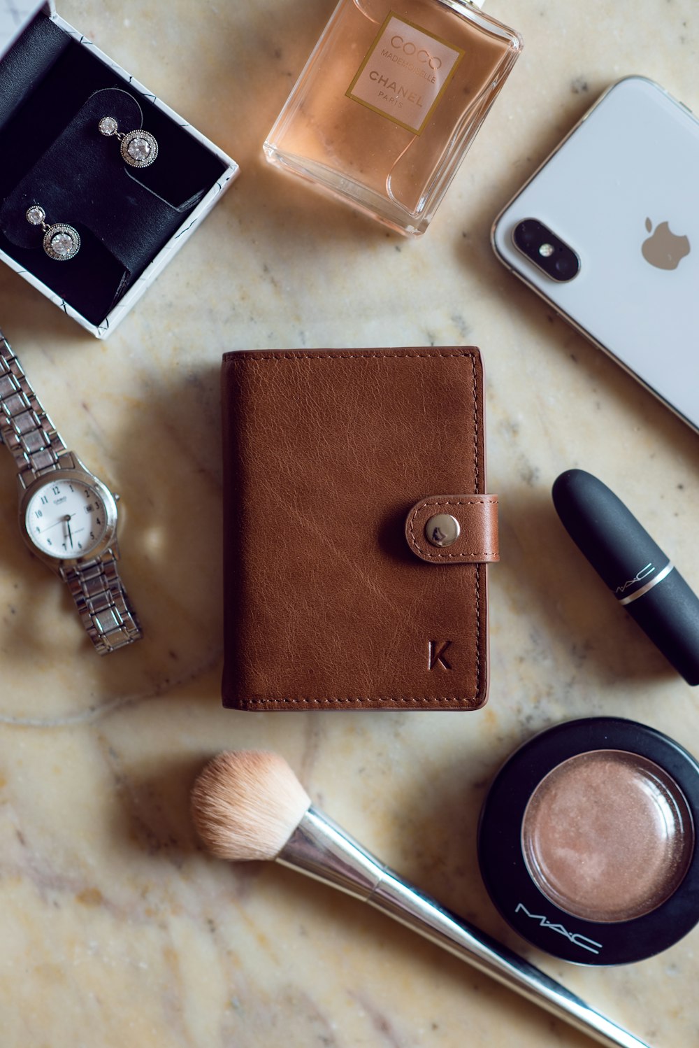 brown leather long wallet beside silver round analog watch