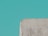 A textured, roughly cut piece of concrete or stone appears in the lower part of the image against a solid teal background.