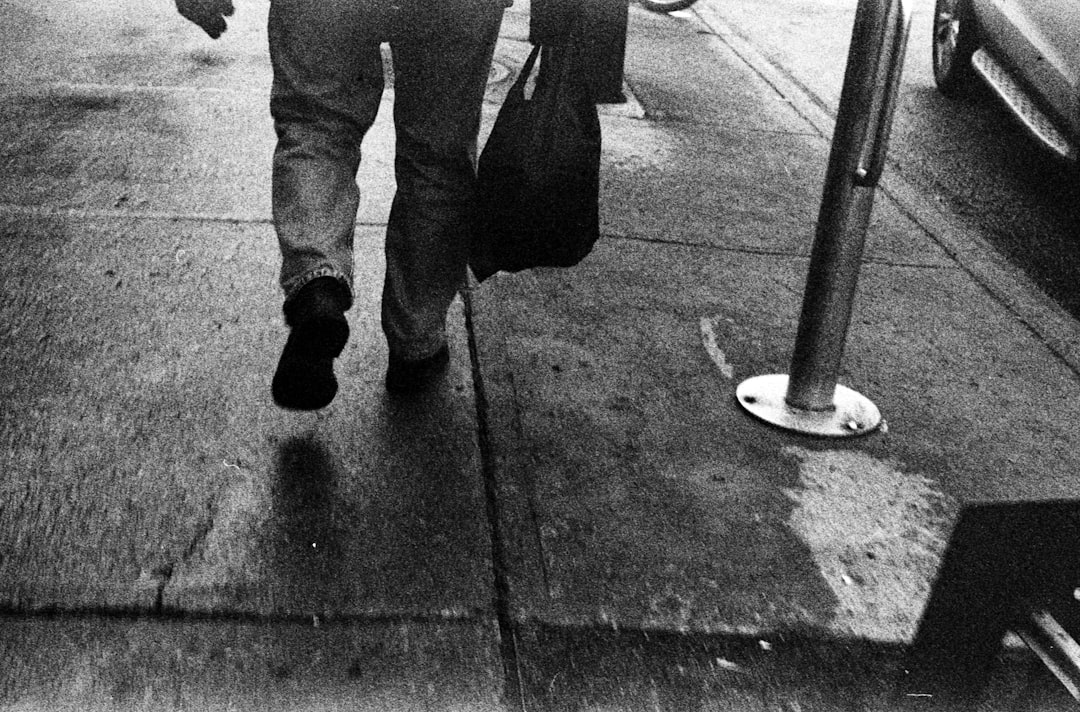 person in black pants and black boots standing on sidewalk