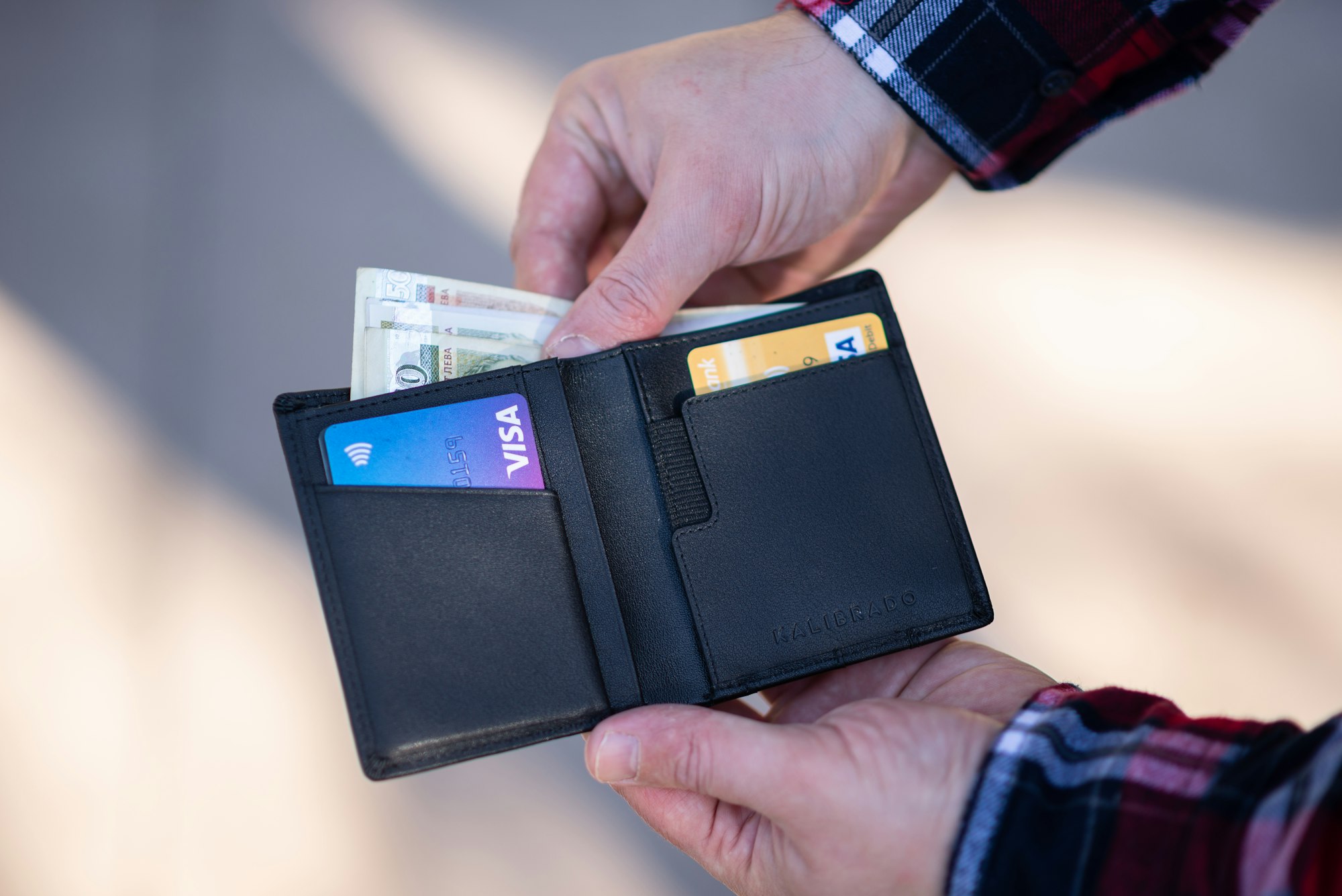 A person pulling notes out of their black wallet
