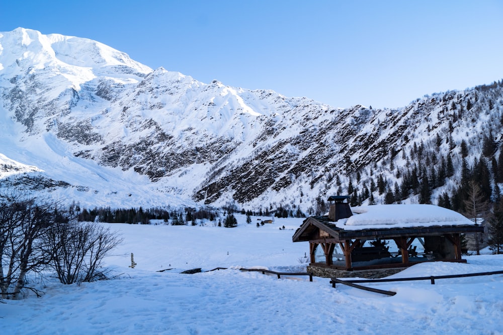 brown wooden house on snow covered ground near snow covered mountain during daytime