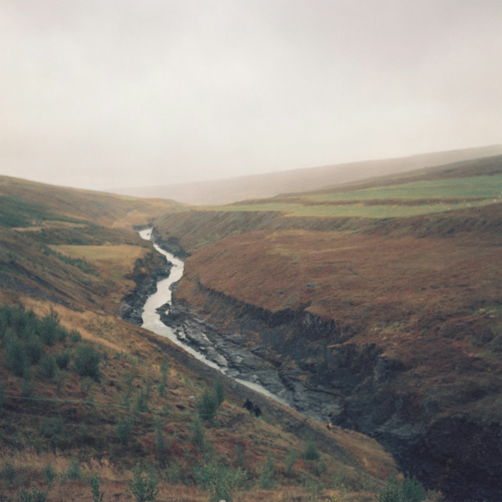 river in the middle of green and brown mountains