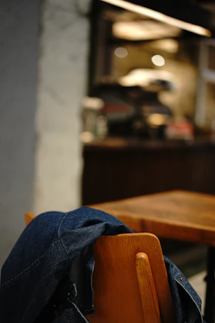 Close-up of a casual denim jacket draped over a chair in a bright, airy room.