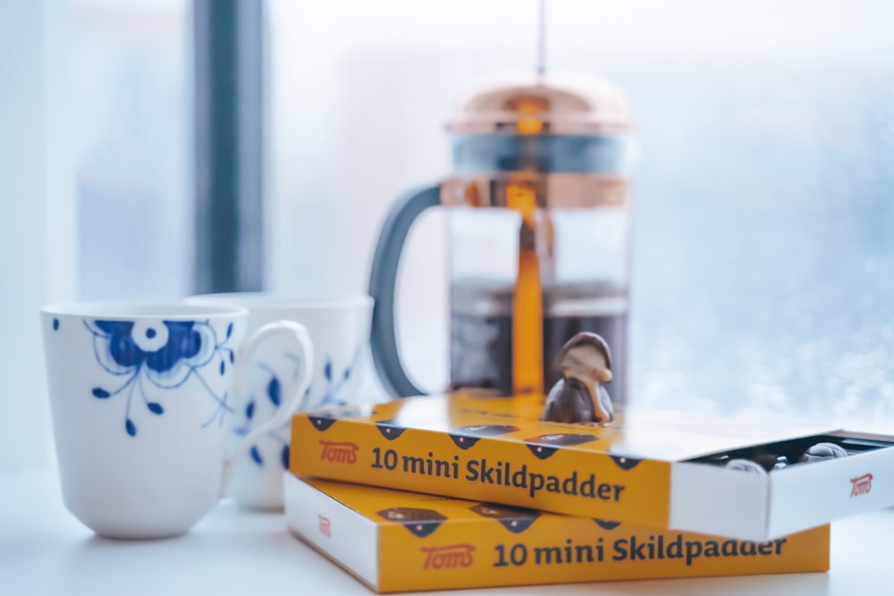 white and blue ceramic mug beside yellow and white box