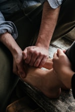 Close-up of hands gently applying reflexology on feet in a calm setting.