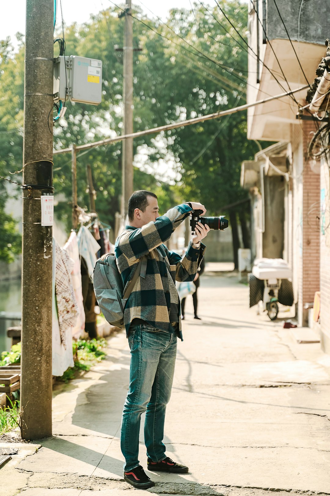 man in white and black plaid dress shirt taking photo using dslr camera