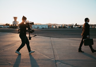 man in black jacket and pants standing on gray concrete floor during sunset