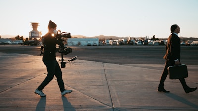 man in black jacket and pants standing on gray concrete floor during sunset