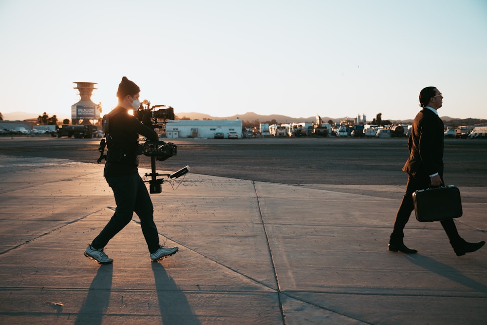 man in black jacket and pants standing on gray concrete floor during sunset