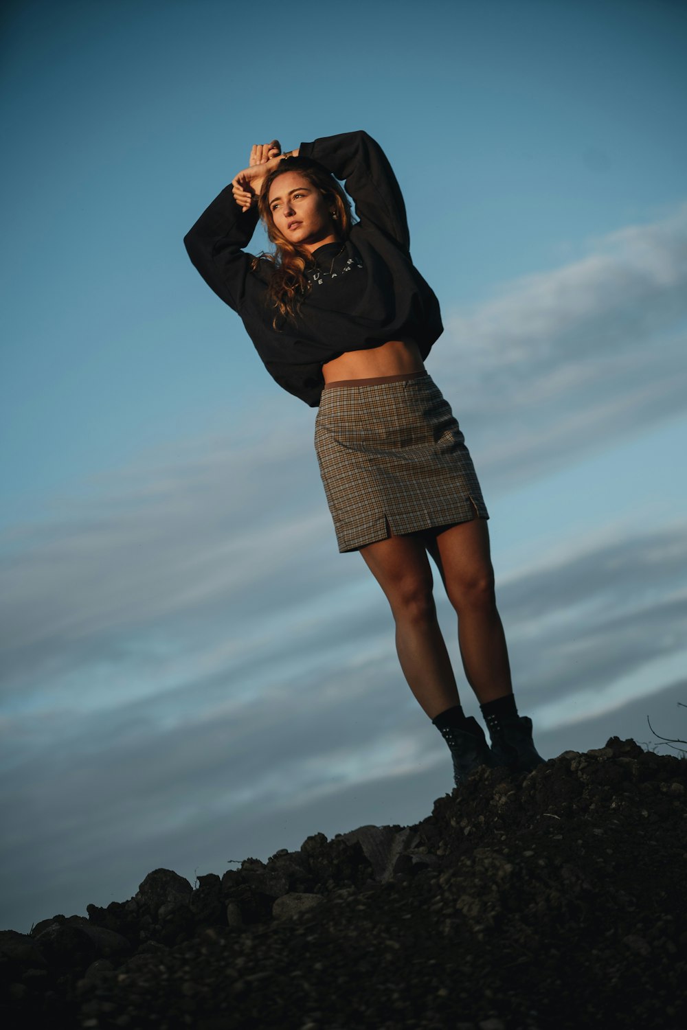 woman in black long sleeve shirt and gray skirt standing on rock during daytime