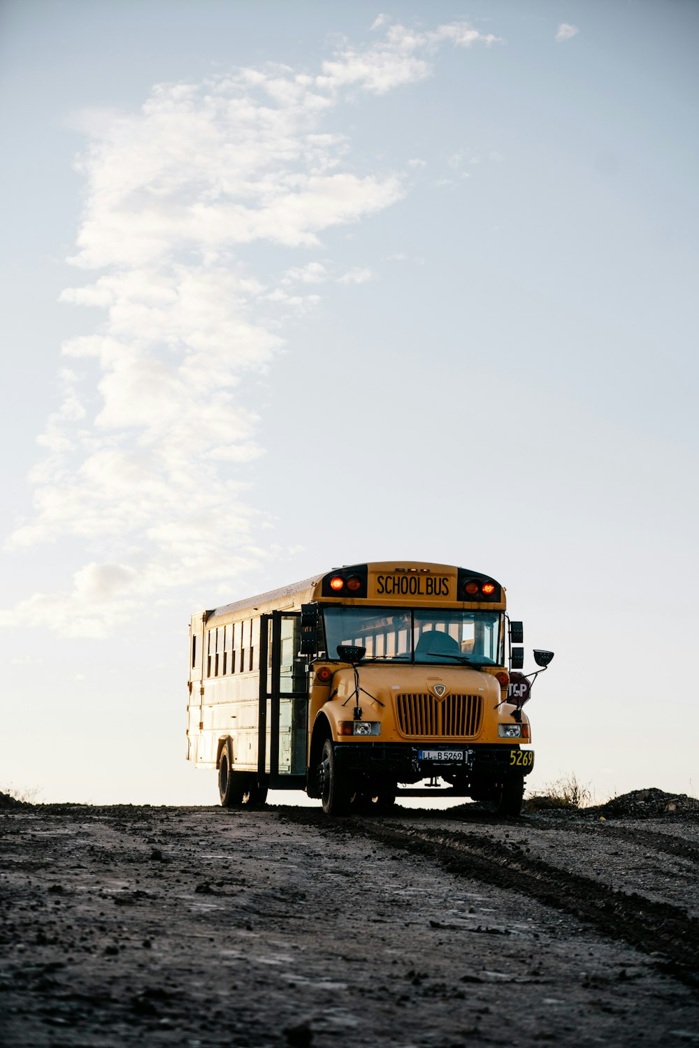 日中の白い曇り空の下、雪に覆われた地面を走る黄色いスクールバス