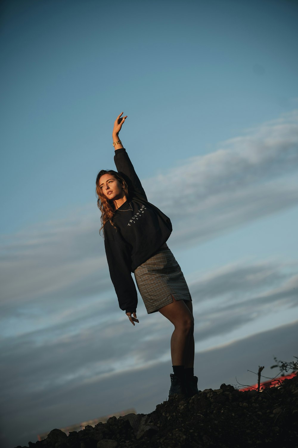 woman in black long sleeve shirt and gray skirt standing under blue sky during daytime