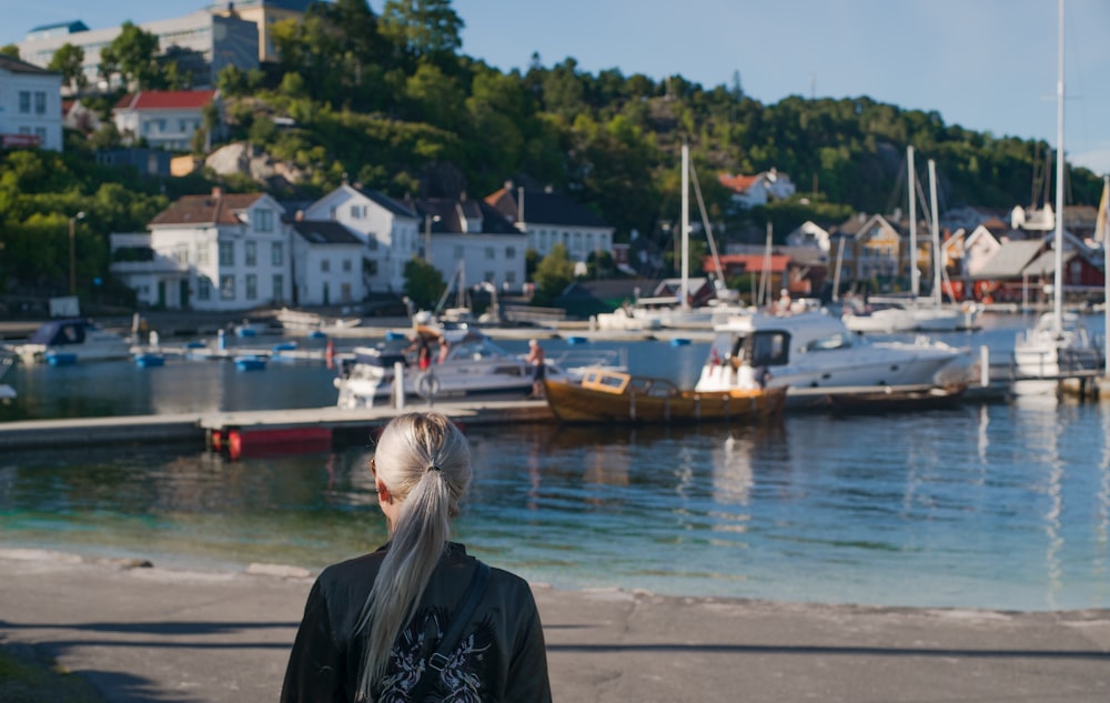 woman in black jacket standing near body of water during daytime