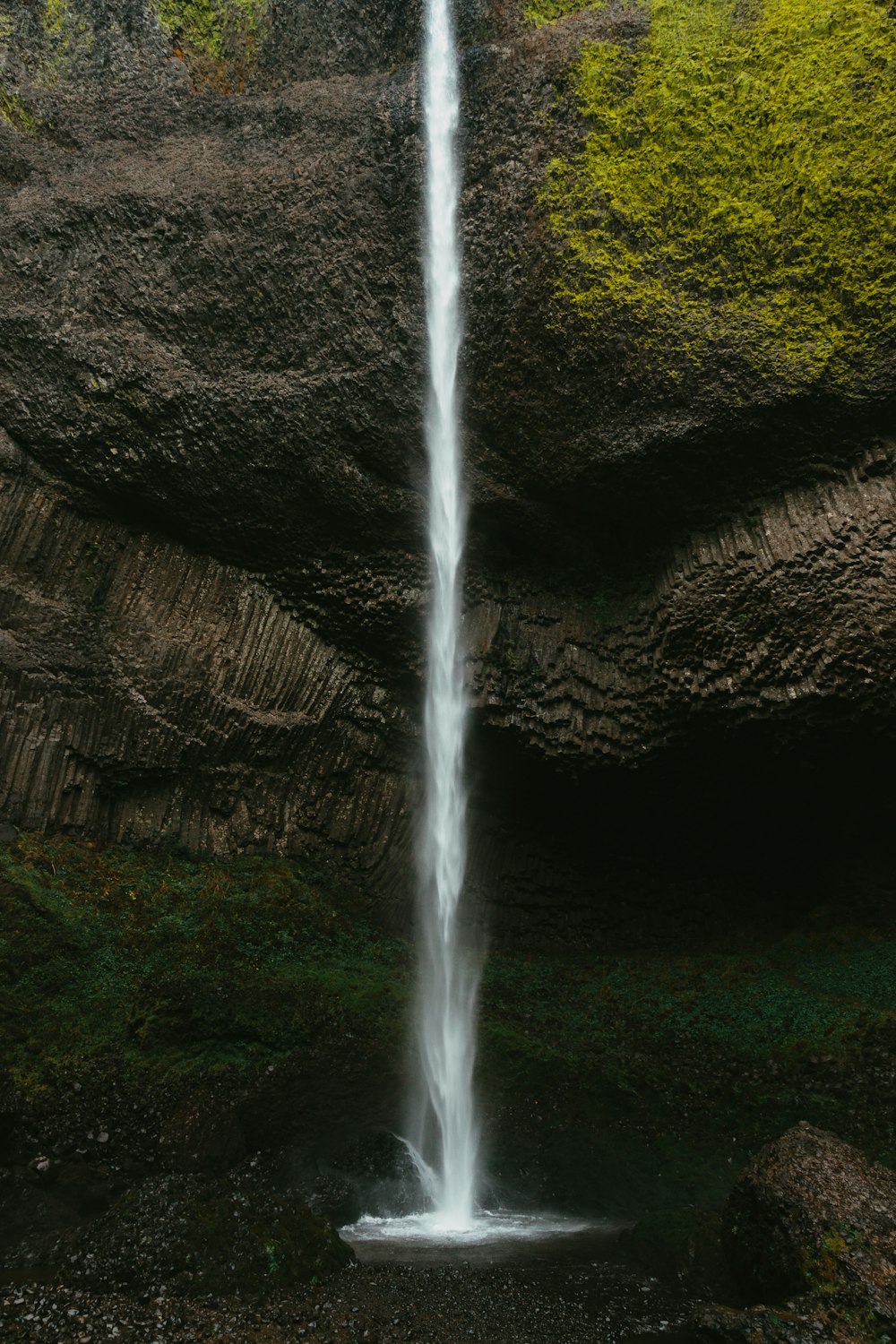 water falls on brown rocky mountain during daytime