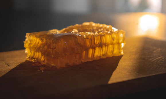 Close-up of golden jaggery blocks stacked on a rustic wooden table with soft natural light highlighting their texture.