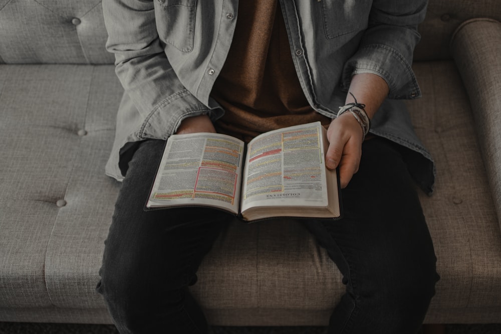 person in gray denim jacket reading book