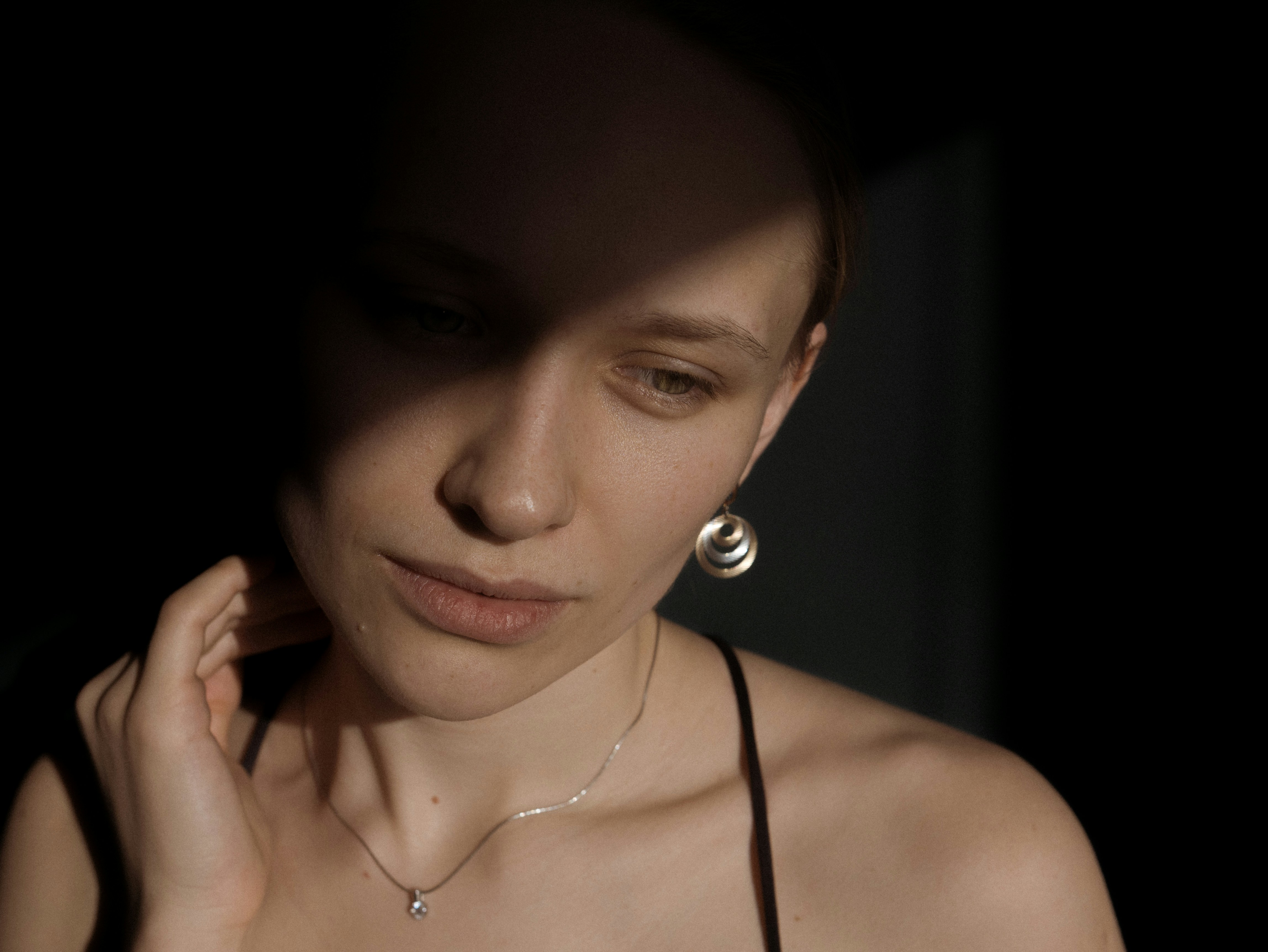 woman in black spaghetti strap top wearing silver earrings